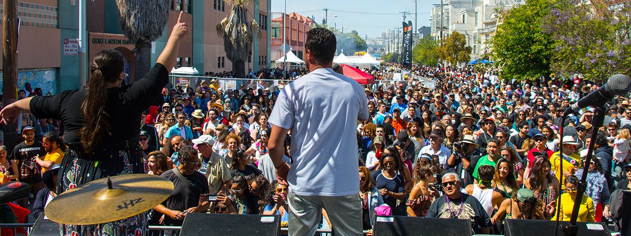 Back view of two band members performing in front of a crowd in an SF street