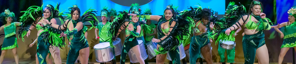 Comparsa with drummers and dancers dressed in green and black with feathers